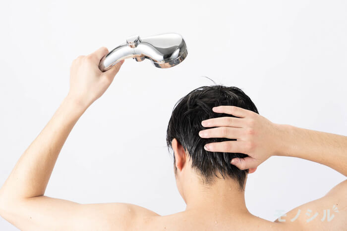 シャンプー前にお湯洗い後頭部にシャワーをあてる男性