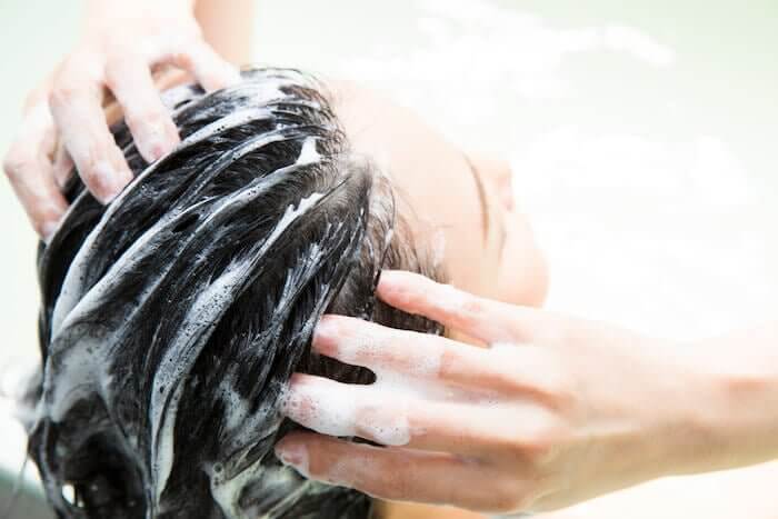 泡立てたシャンプーで頭皮を洗っている女性
