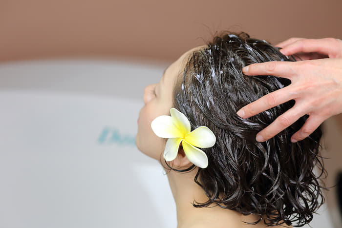 髪をシャンプーで洗われている女性